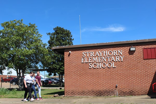 Students walking in front of school building on a sunny day